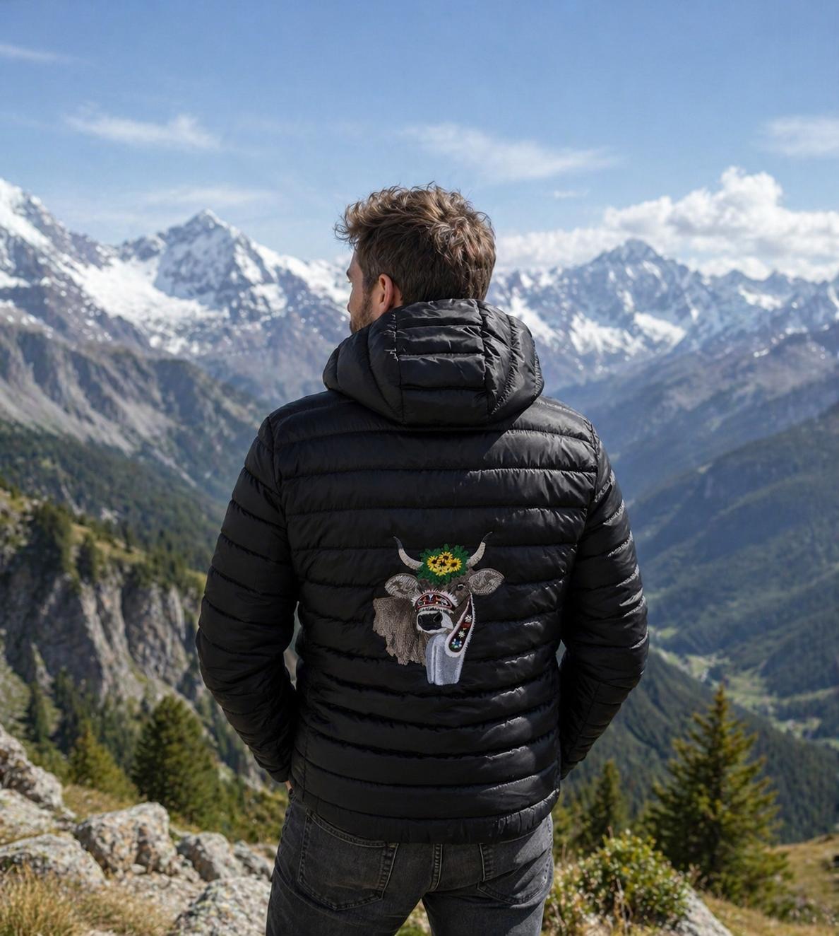 WhatsApp Image 2026-04-30 at 1352385 | fil - magic Stickerei Berther Man in a black puffer jacket seen from behind, overlooking snow-capped mountains under a blue sky.