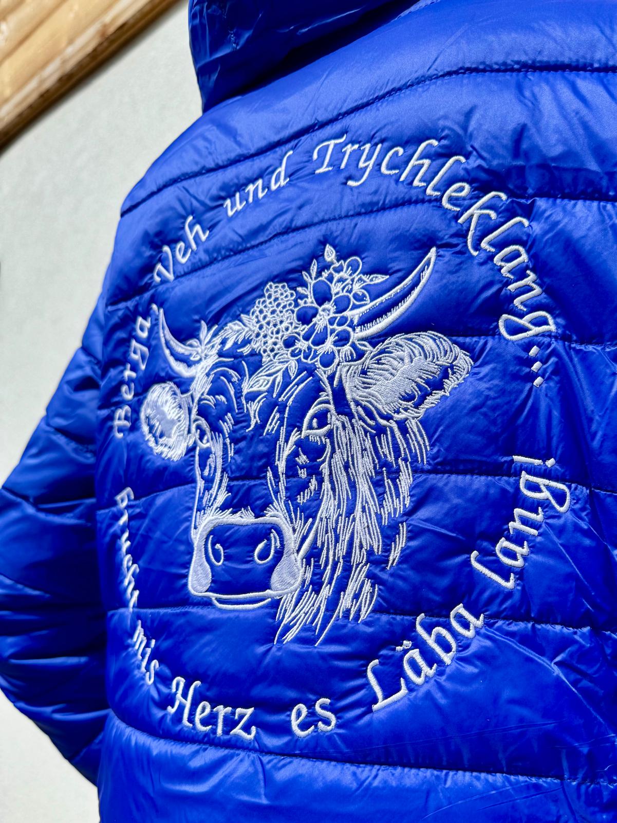 WhatsApp Image 2026-04-30 at 135353 | fil - magic Stickerei Berther Blue quilted jacket with white embroidery of a goat and decorative flowers.