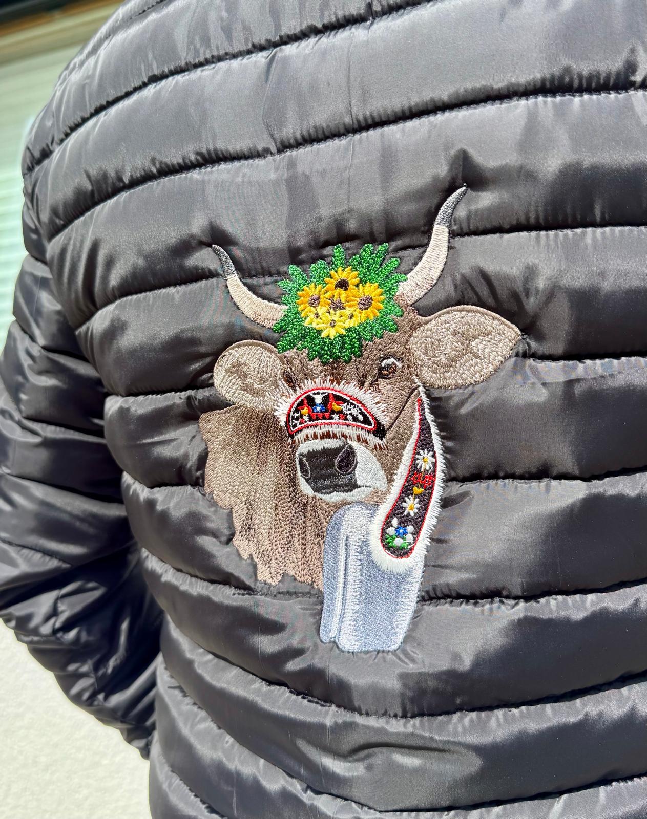 WhatsApp Image 2026-04-30 at 13535311 | fil - magic Stickerei Berther Black puffer jacket featuring a decorative embroidered moose head patch with a sunflower crown and a floral scarf on its muzzle area.
