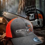 Gray and orange trucker cap with a stitched 'NO LIMIT' patch and a chainsaw graphic, resting on a tree stump in a forest with a chainsaw in the background.