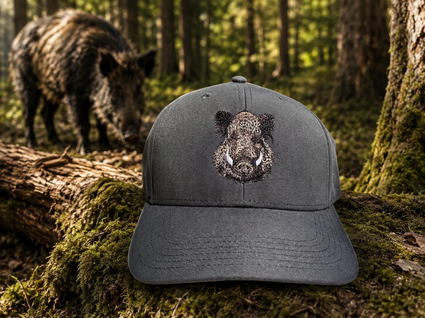 WhatsApp Image 2026-08-22 at 1728066 | fil - magic Stickerei Berther Charcoal baseball cap with a boar head embroidery, placed on a mossy log in a forest setting.